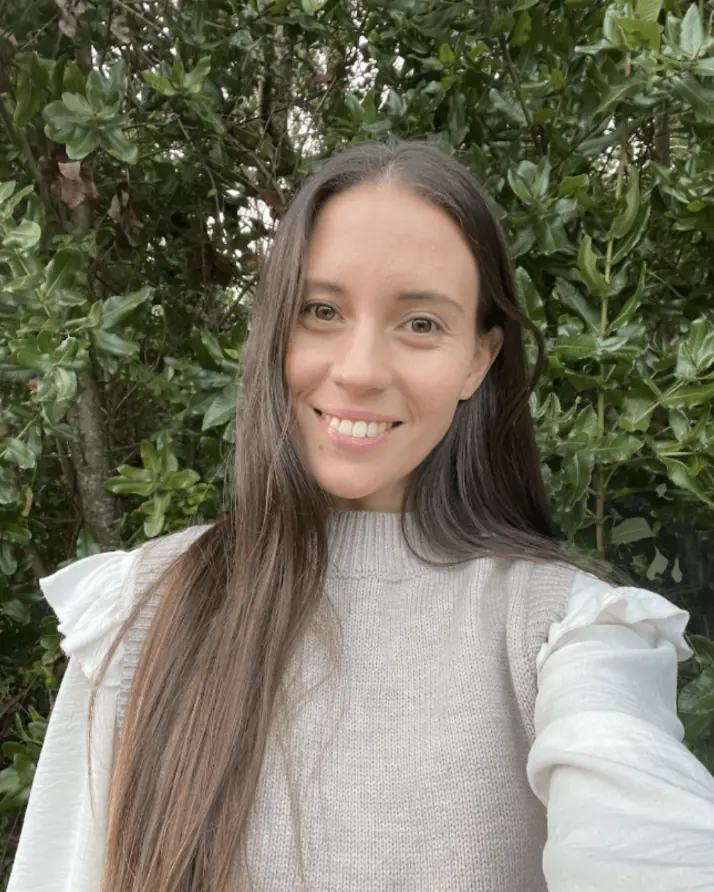Camila, mentora de El Jardín, sonriendo frente a un fondo de hojas verdes